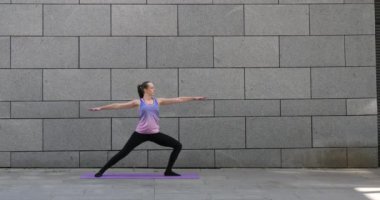 Kadın uygulamaları yoga fitness egzersiz şehrin gri kentsel zemin üzerine pembe mat