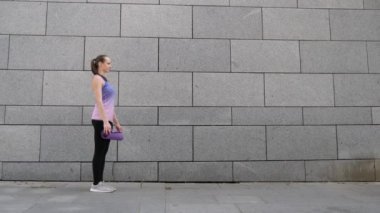 Kadın apart yoga mat gri Kentsel şehir arka plan üzerinde rulo. Özgürlük, sağlık ve yoga kavramı. Atış kapatın
