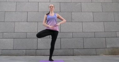 Kadın uygulamaları yoga fitness egzersiz şehrin gri kentsel zemin üzerine pembe mat