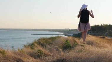 Güneşli okyanus deniz kumsalda otostop ve yürüyüş Gezgin kadın. Bir gezintiye arayan genç mutlu backpacker kadın yağdırdığı ülke yolda bir yolculuğa başlamak için
