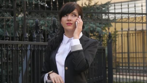 Attractive brunette businesswoman talking on mobile phone with client. — Stock Video