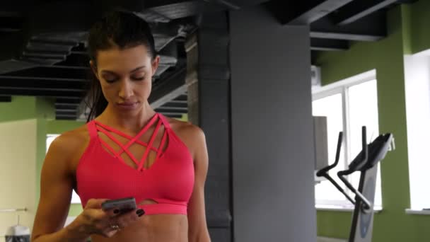 Kobieta Fit sportowe mieszane rasy jest chodzenie sms SMS-y w siłownia sport na telefon — Wideo stockowe