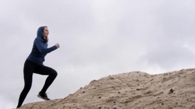 Konsantre kadın jogger ince bir rakam ile çöl Çalıştır devreye girer. Arka planı karanlık fırtına bulutları gökyüzüne.