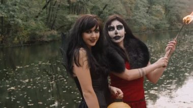 Genç halloween kız arkadaşlar orman Park ürkütücü kabak açık turuncu geleneksel sonbahar tatil sembolü ile eğleniyor siyah ve kırmızı cadı Giydir
