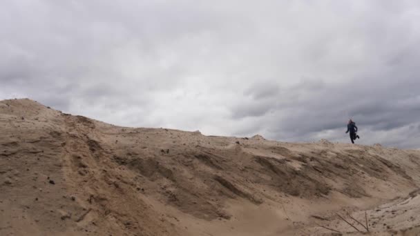 Concentrated woman jogger with a slender figure is engaged in run at desert. Dark storm clouds sky at background. — Stock Video