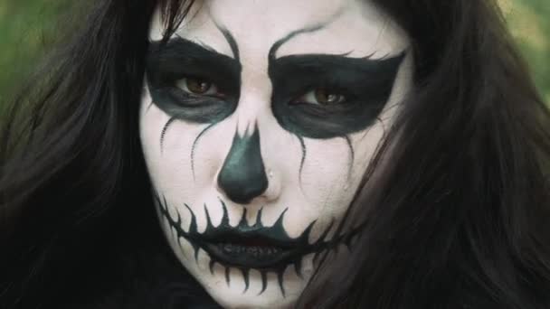 Young woman in scary black and white halloween make up looking into camera. — Stock Video