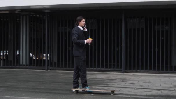 Mladá atraktivní obchodní muž office pracovník na koni skateboard do práce. Pití kávy latte a telefonuju. Smíšené rasy Latinské hispánský etnika. — Stock video