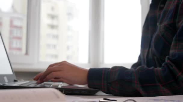 Joven gerente de finanzas trabajando en el portátil. Documentos comerciales en mesa de oficina con teléfono inteligente y computadora portátil y gráfico financiero con gráficos de diagramas de redes sociales — Vídeo de stock