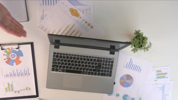 Close up vista superior de dois empresários apertando as mãos contra uma tabela com gráficos financeiros, caderno e diagramas de negócios — Vídeo de Stock