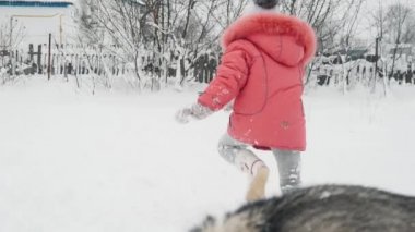 Genç kız açık havada ağır çekimde karda Siberian dış yapraklar malamute köpekle oynamayı