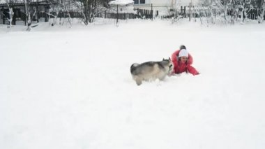 Genç kız açık havada ağır çekimde karda Siberian dış yapraklar malamute köpekle oynamayı