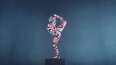 Genç esnek sarışın sirk acrobat Studio kostüm poz. Equilibre denge amut bir küp üzerinde yapıyor.