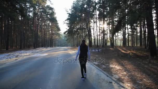 Ung kvinna med en slank figur bedriver gymnastik vid soluppgången. Hon gör en springa längs skogen. — Stockvideo