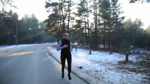 Mladá žena s štíhlá postava se zabývá gymnastika při východu slunce. Ona dělá běh podél lesa. — Stock video