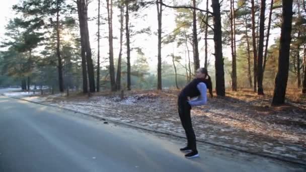 Спортсменка середнього віку, що тягнеться в зеленому листяному лісі на брудній дорозі перед бігом . — стокове відео