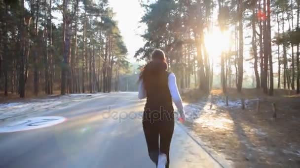 A mulher jovem com um número esbelto envolve-se na ginástica no amanhecer. Ela corre ao longo da floresta . — Vídeo de Stock