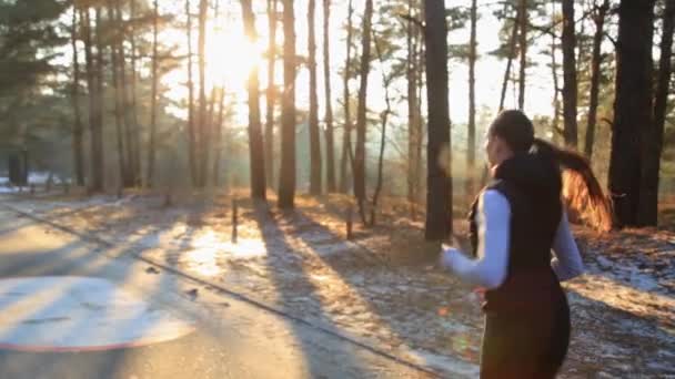 Jonge vrouw met een slank figuur is betrokken bij Turnen bij zonsopgang. Ze maakt een punt langs het bos. — Stockvideo
