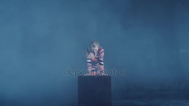 Jeune acrobate de cirque blonde souple posant en studio en costume. Faire équilibre équilibre handstand sur un cube .