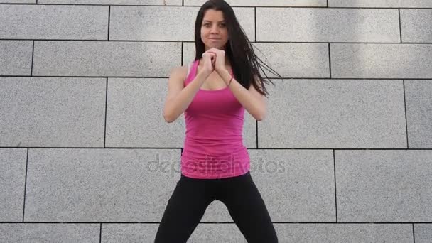 Glücklich junge brünette Fitness-Sportlerin beim Training im Freien in der Stadt vor städtischem Hintergrund. — Stockvideo