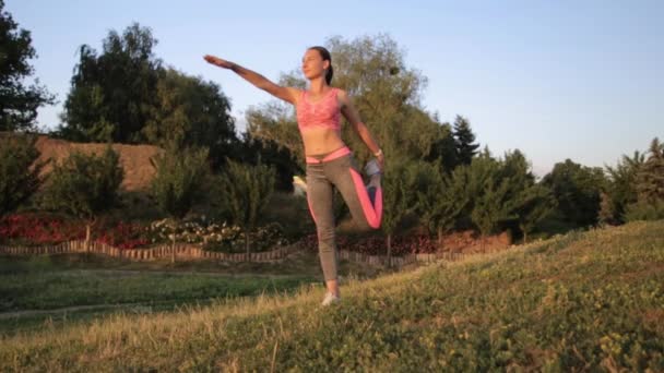 Chica hipster fitness en ropa deportiva de moda haciendo ejercicio de yoga fitness en la calle, deportes al aire libre . — Vídeo de stock