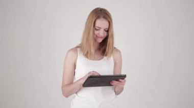 Tablo Pc bilgisayar ile ışık gri arka plan üzerinde duran mutlu kadın. Alan metni kopyalayın.