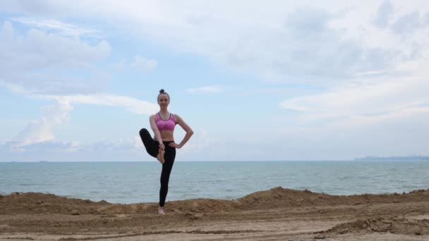 Kız uygulamaları yoga fitness egzersiz savaşçı poz okyanus plaj yakınında — Stok video