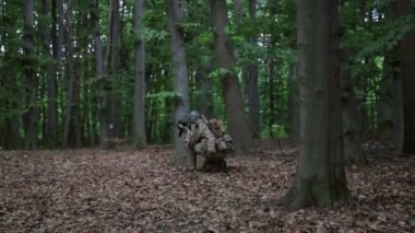 Silahlarını orman çalıların taşıyan bir oluşumunda çalıştıran gerilla savaşçıları kadrosu.