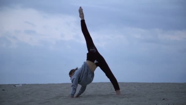 Hermosa mujer atlética caucásica en traje de cuerpo beige estirarse al aire libre al amanecer. Mujer en forma haciendo entrenamiento de yoga. Motivación física . — Vídeo de stock