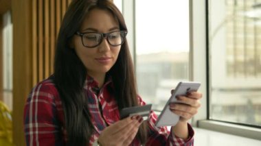 Kredi kartı tutan ve dizüstü bilgisayar kullanan genç karışık yarış hipster kadın