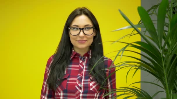 Hipster mujer de raza mixta usando smartwatch sobre fondo amarillo — Vídeos de Stock