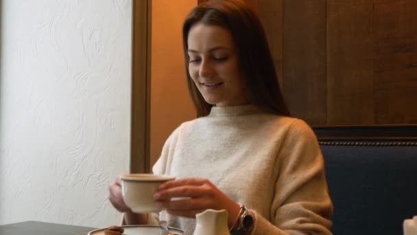 Ділова жінка зі смартфоном п'є каву в кафе — стокове відео