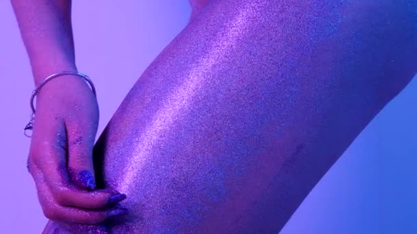 Hermosa mujer pintando con chispas en su pierna en luz ultravioleta — Vídeo de stock