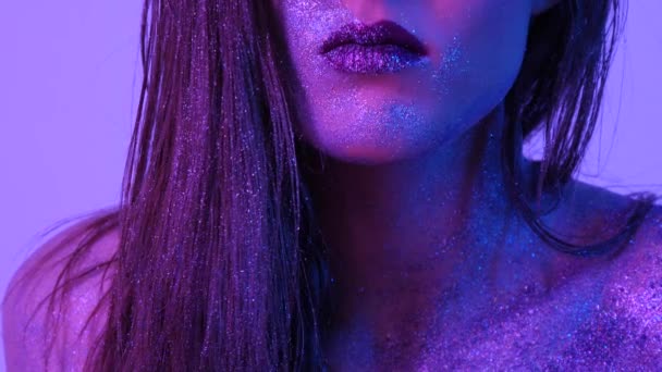 Bella donna con scintille sul viso in luce ultravioletta — Video Stock