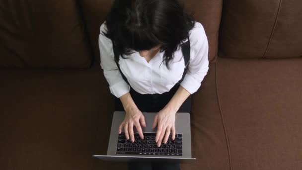 Mujer joven usando el ordenador portátil en casa sentado en el sofá — Vídeo de stock