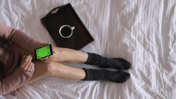 Mujer en la cama bebiendo café y comprobar el teléfono inteligente — Vídeos de Stock