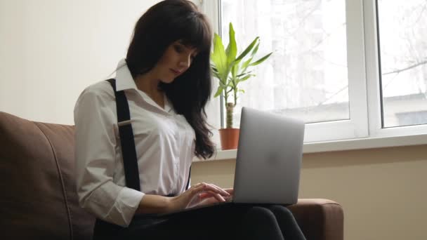 Jonge vrouw met laptop thuis zittend op de Bank — Stockvideo