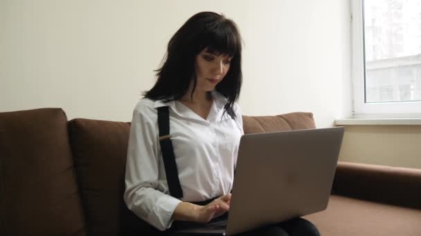 Young woman using laptop at home sitting on sofa — Stock Video