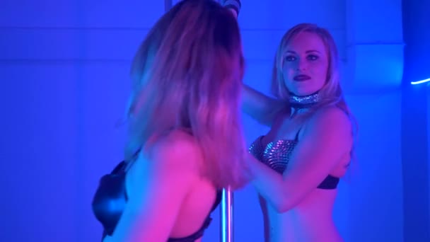 Дві молоді сексуальні стрункі жінки полюс танцює з пілоном в темному інтер'єрі — стокове відео