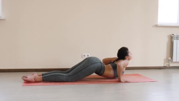 Фитнес-женщина делает растяжку тренировки на коврик для упражнений. Молодая женщина, занимающаяся спортом в помещении — стоковое видео