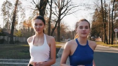 Açık havada park beton yolda ağır çekimde çalışan iki atletik kadın. Sağlıklı fitness kavramı