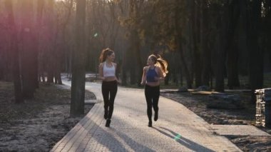 Açık havada park beton yolda ağır çekimde çalışan iki atletik kadın. Sağlıklı fitness kavramı