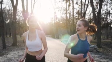 Açık havada park beton yolda ağır çekimde çalışan iki atletik kadın. Sağlıklı fitness kavramı