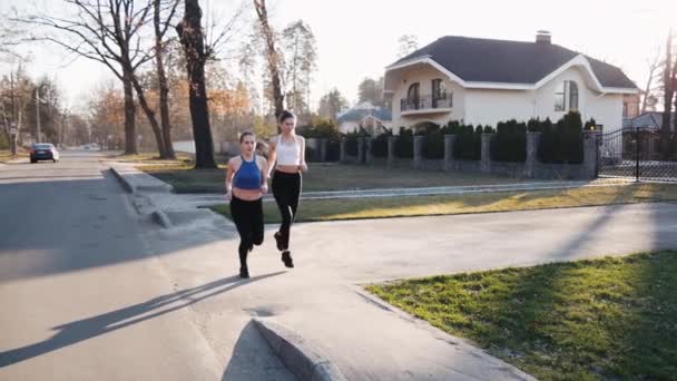 Two athletic woman running outdoors in slow motion on concrete track in park. Healthy fitness concept — Stock Video