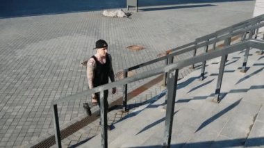 Çağdaş hip hop sokak dansçısı hipster adam dövme ile merdivenlerden tırmanıyor