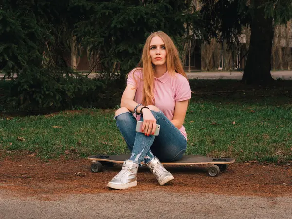 Zenzero rossa donna seduta su skateboard longboard all'alba al parco estivo — Foto Stock