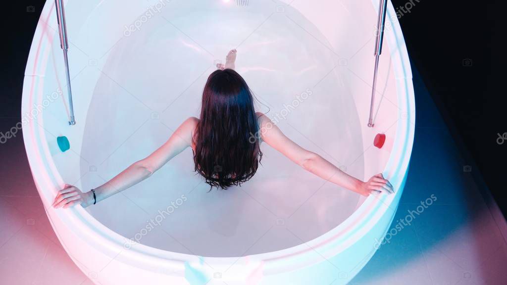 Young woman floating in Spa bath or swimming pool, she is very relaxed. Welness concept