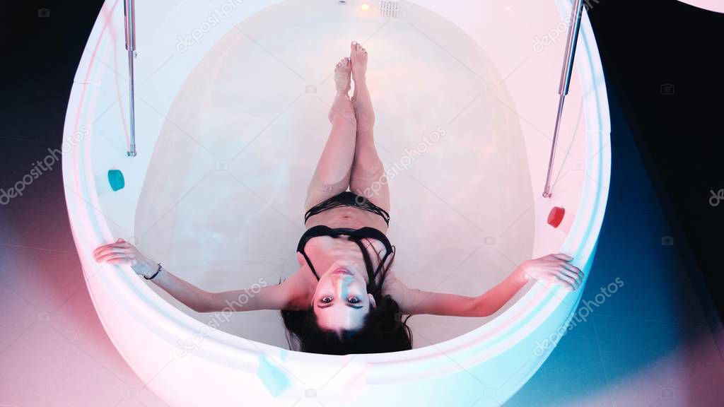 Young woman floating in Spa bath or swimming pool, she is very relaxed. Welness concept