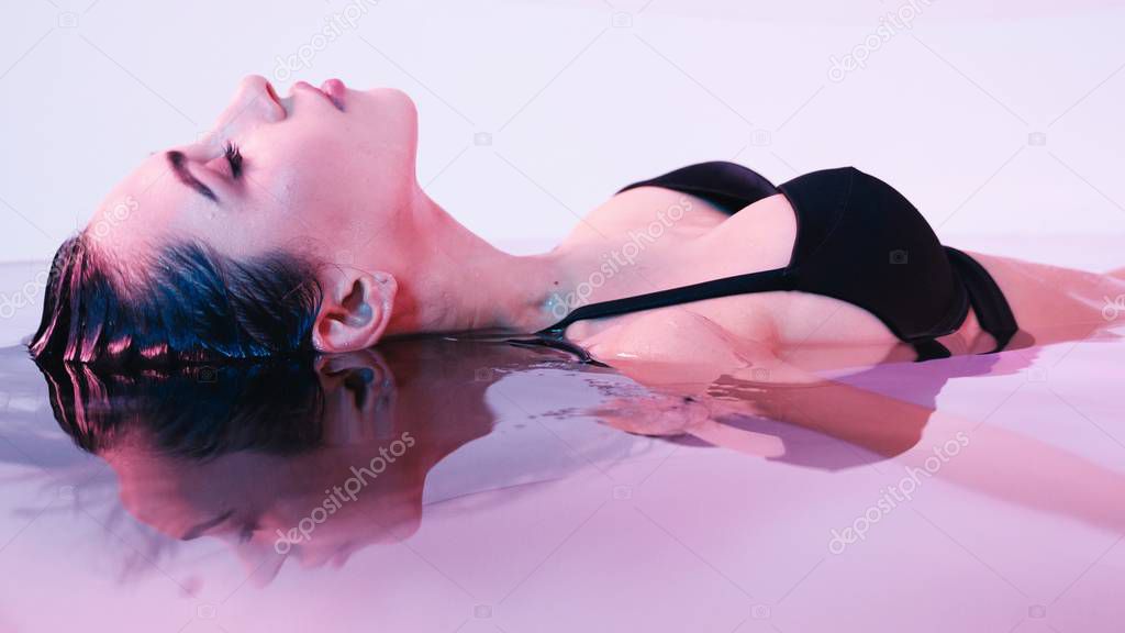 Young woman floating in Spa bath or swimming pool, she is very relaxed. Welness concept