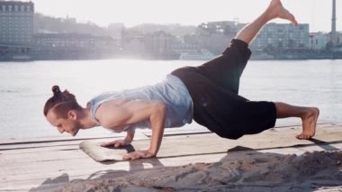 Genç Beyaz adam tarafından pratik yoga fitness egzersiz city adlı arka plan ile sakin Nehri yakınında sahilde rahatlatıcı