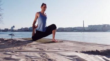 Genç Beyaz adam tarafından pratik yoga fitness egzersiz city adlı arka plan ile sakin Nehri yakınında sahilde rahatlatıcı